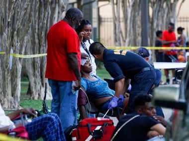 A Dallas Fire-Rescue paramedic checks out a woman that fainted at the scene of a shooting at...