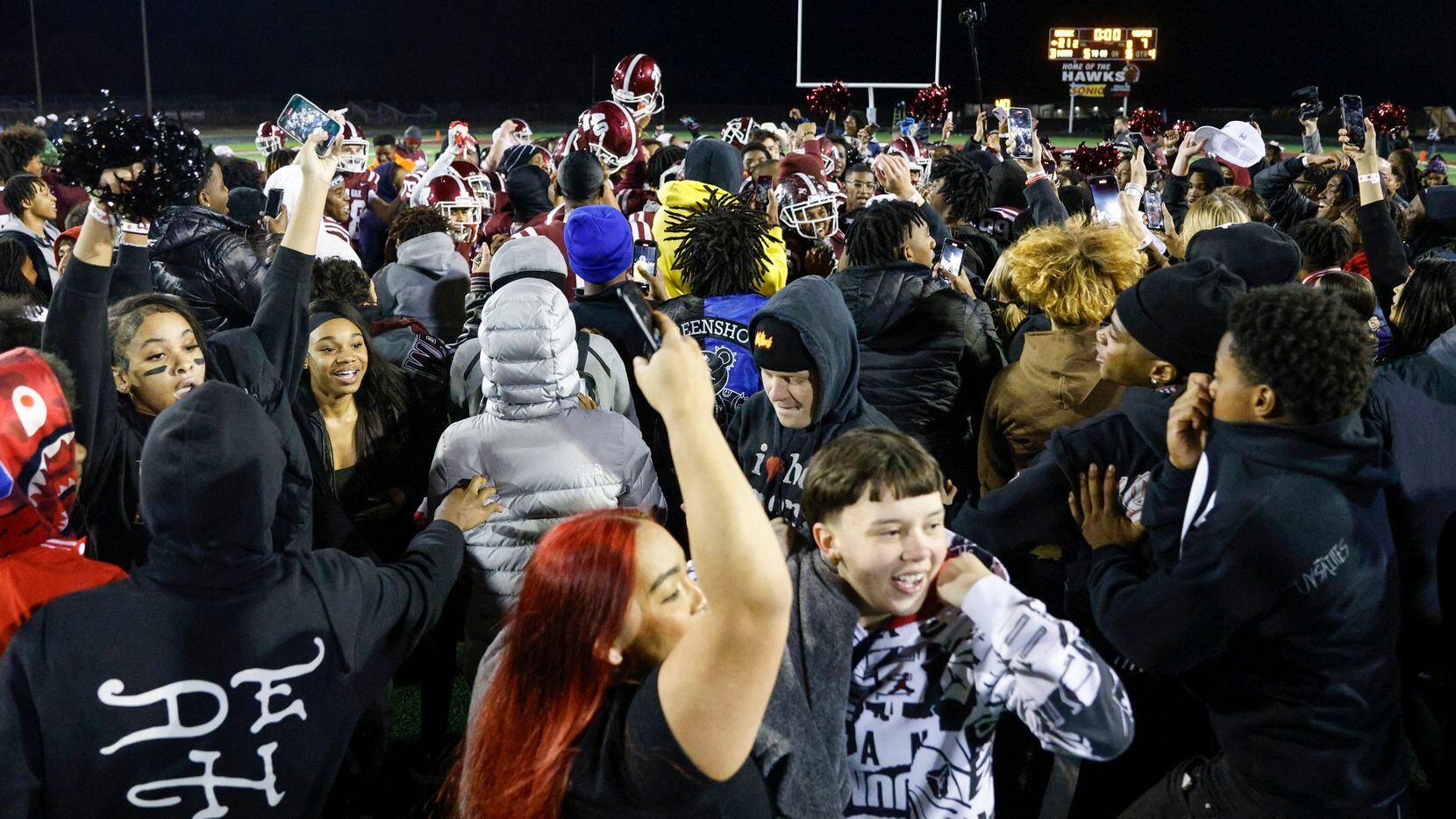 Red Oak students celebrate with the football team after rushing the field after winning a...