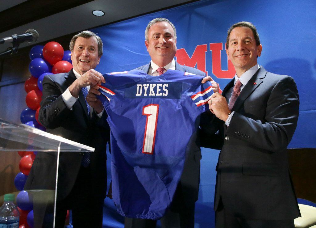 New SMU head football coach Sonny Dykes, center, holds up a jersey with university president...