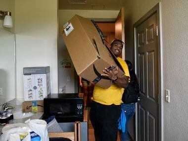 Student volunteer Joseph Lashley (left) carries a cardboard box for an incoming freshman as...