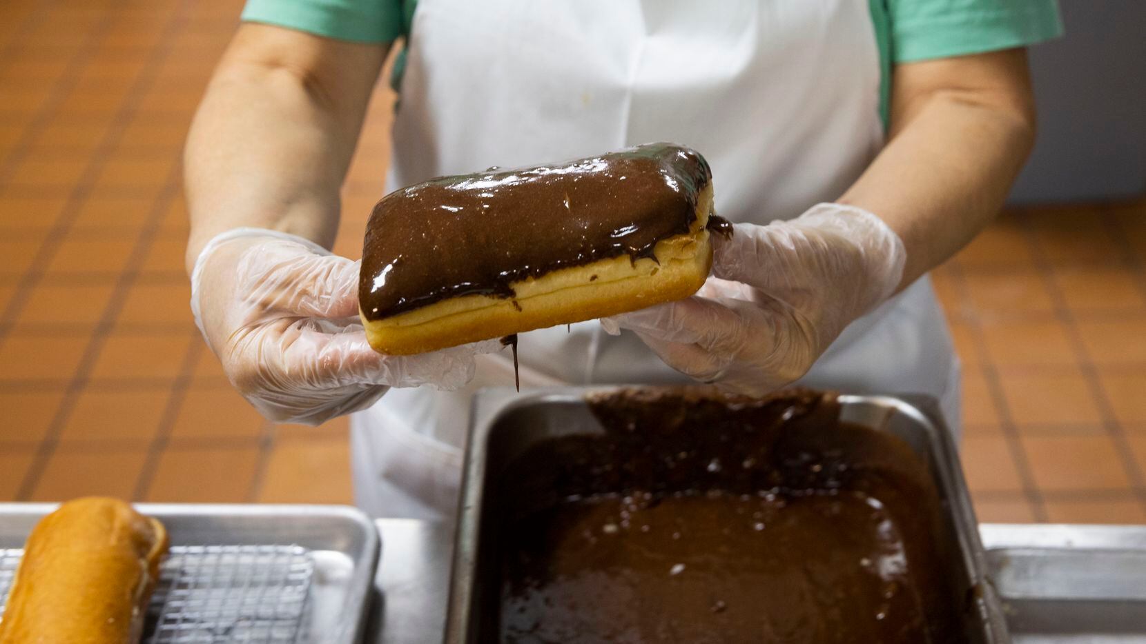Maria Mendoza, who has been working at Lone Star Donuts for over 30 years, glazes a...