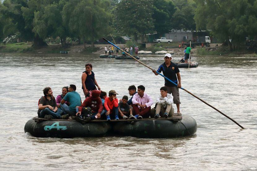 Un grupo de personas cruzan el Río Suchiate en una balsa improvisada desde Guatemala a...