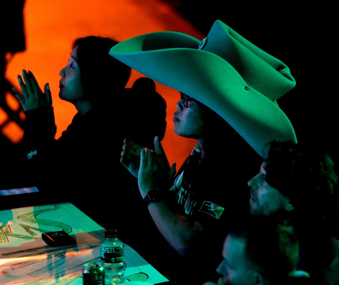 Framed by other Esports enthusiasts, a fan sports a Texas-sized cowboy hat as they follow...