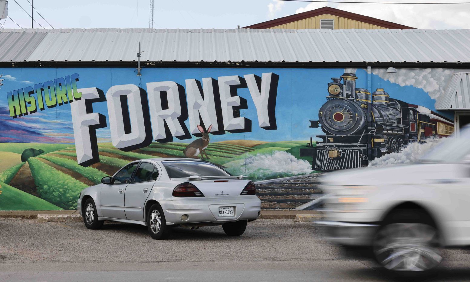 Traffic passes by a mural in downtown Forney.