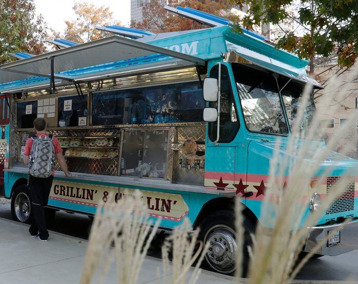 A man orders at a food truck parked at Klyde Warren Park. 
