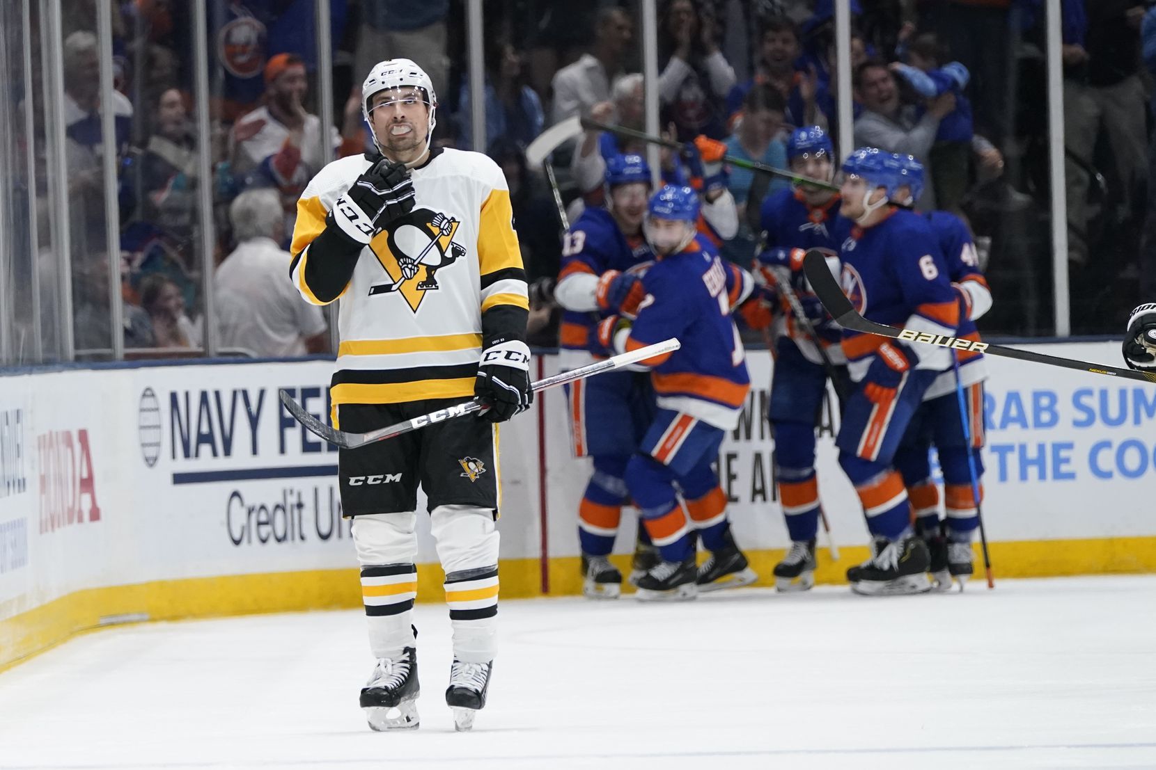 Pittsburgh Penguins' Cody Ceci, left, reacts as the New York Islanders celebrate a goal by Jordan Eberle during the third period of Game 4 of an NHL hockey Stanley Cup first-round playoff series, Saturday, May 22, 2021, in Uniondale, N.Y. The Islanders won 4-1.