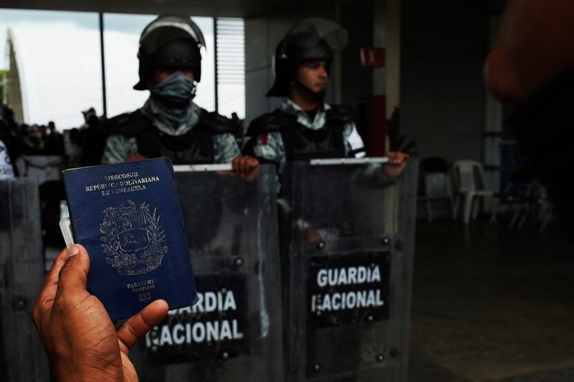 ARCHIVO - Un migrante sostiene su pasaporte venezolano frente al Centro de Atención Integral...
