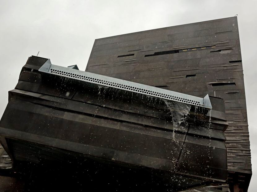 A small waterfall of rain flows off the end of a collection system at the Perot Museum of...