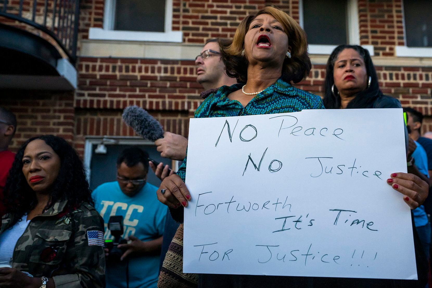 Protestors gather outside the house (not pictured) where Atatiana Jefferson was shot and...