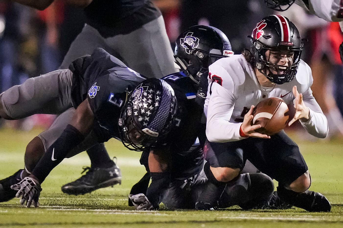 Colleyville Heritage quarterback Luke Ullrich (12) is brought down by Mansfield Summit defensive backs Justyn McDonald (15) and Ahmaad Moses (3) during the first half of the Class 5A Division I Region I final on Friday, Dec. 3, 2021, in North Richland Hills, Texas. (Smiley N. Pool/The Dallas Morning News)