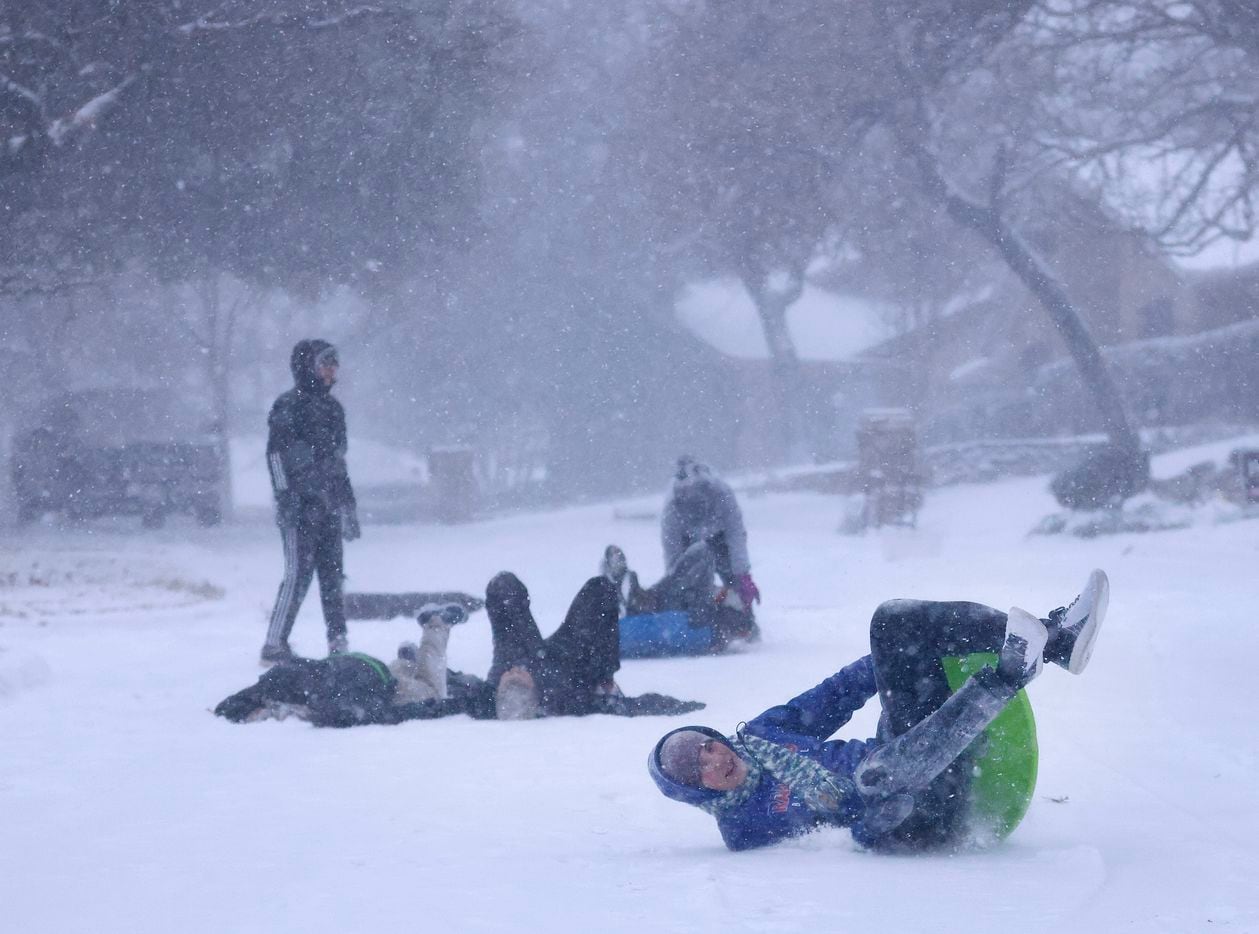 Wyatt Wheeler wipes out as he sleds down a steep snow-covered street in North Arlington,...