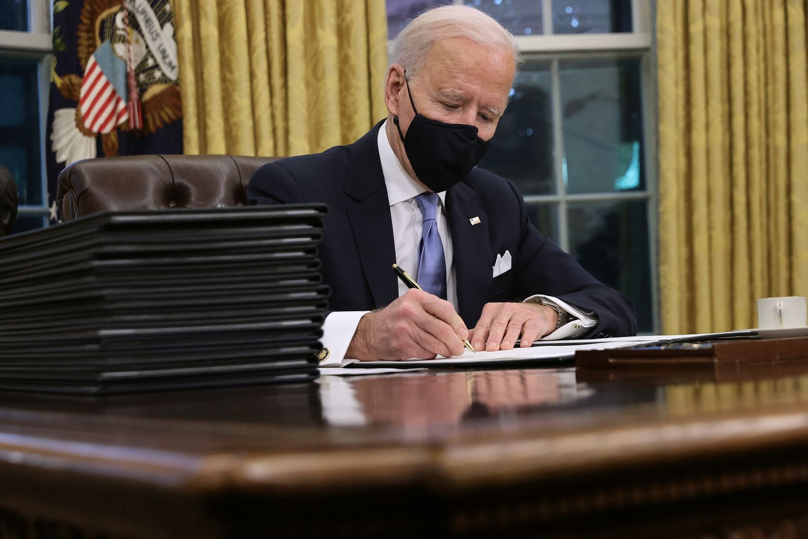 President Joe Biden signs executive orders at the Resolute Desk in the Oval Office just hours after his inauguration on January 20, 2021.
