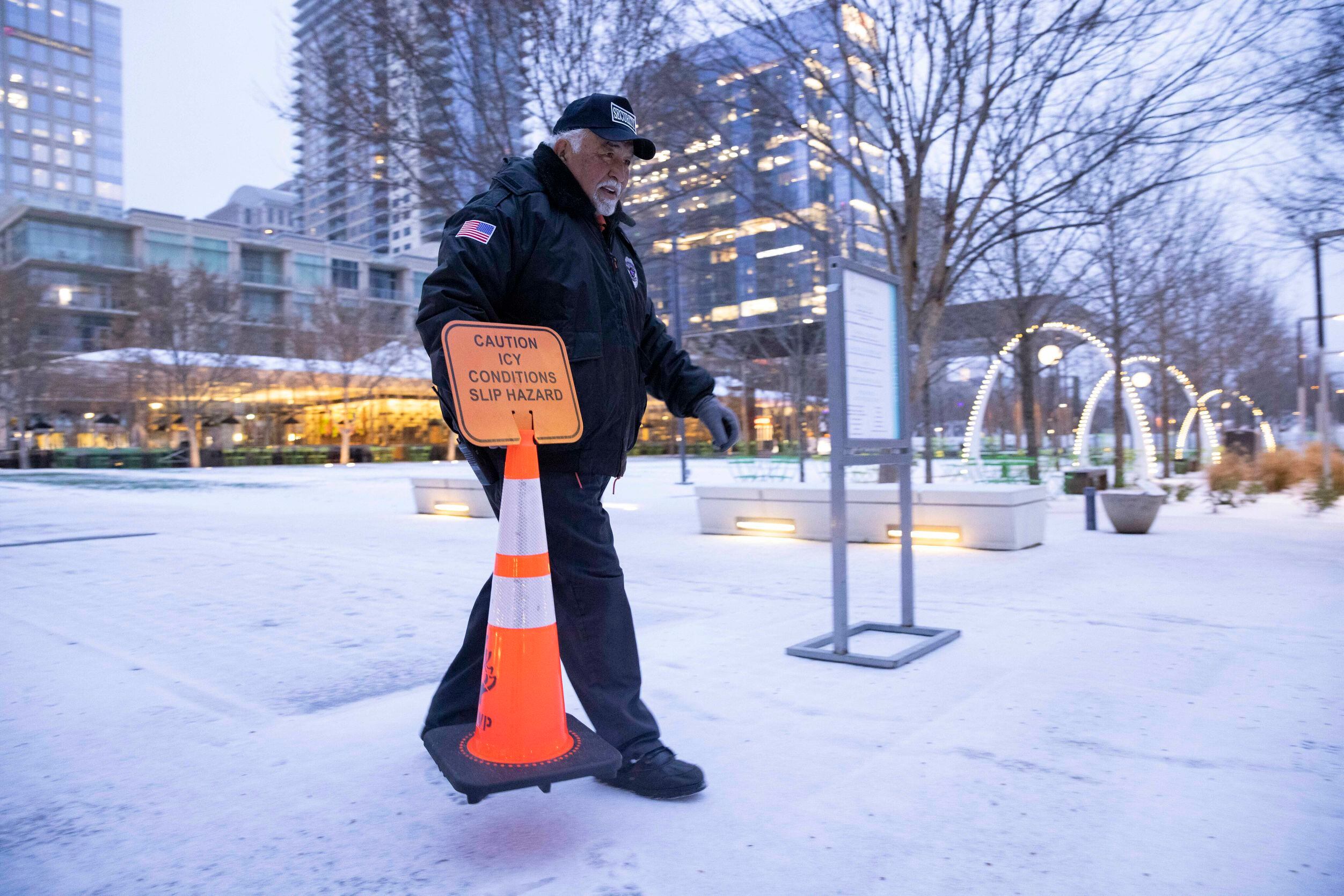 Ernie Muñoz, head of security for Klyde Warren Park, puts up a caution sign warning of slick...