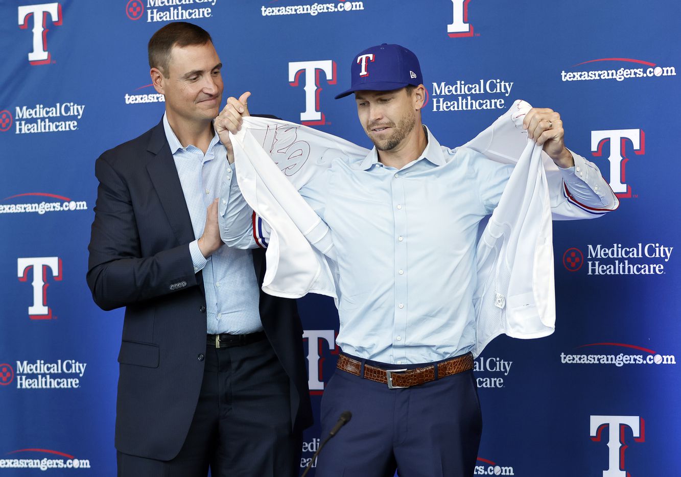 New Texas Rangers starting pitcher Jacob deGrom tries on his new jersey with the assistance...