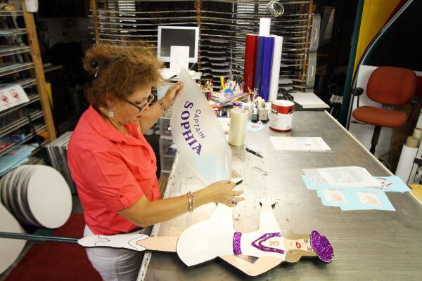 "The Sign Lady" Cindy Villela, peels away decal paper while applying letters to a...