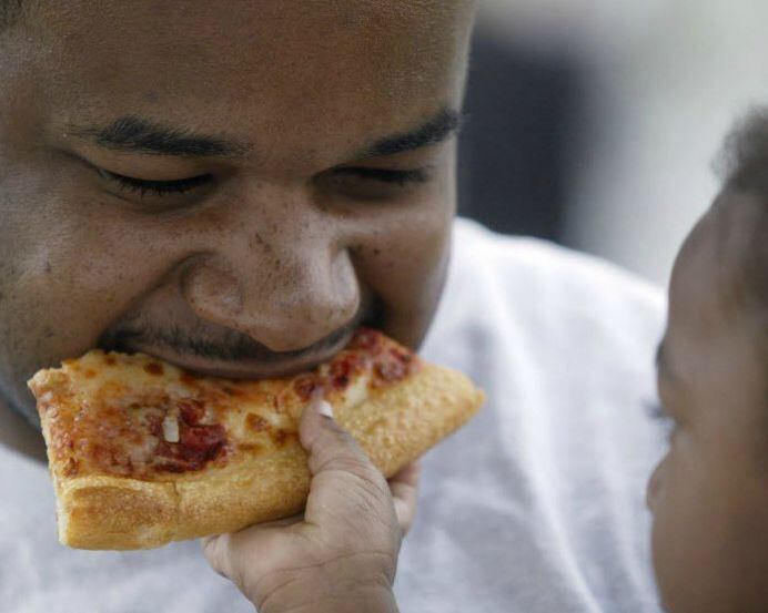 May Shamsid-Deen, 2, feeds her dad a piece of pizza during the Taste of Addison. 