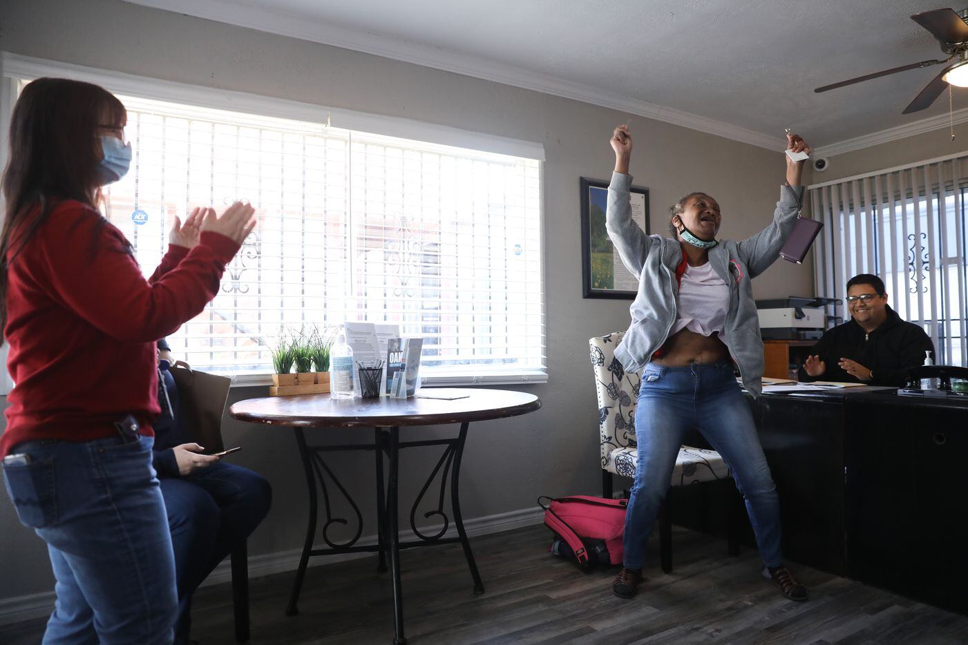 Patricia Freeman (second on the right) jumps up and down with excitement after receiving the key to her new apartment in southern Dallas on November 19, 2021. Staff from The Bridge Homeless Recovery Center and the apartment complex clap for her. (Liesbeth Powers/Special Contributor)