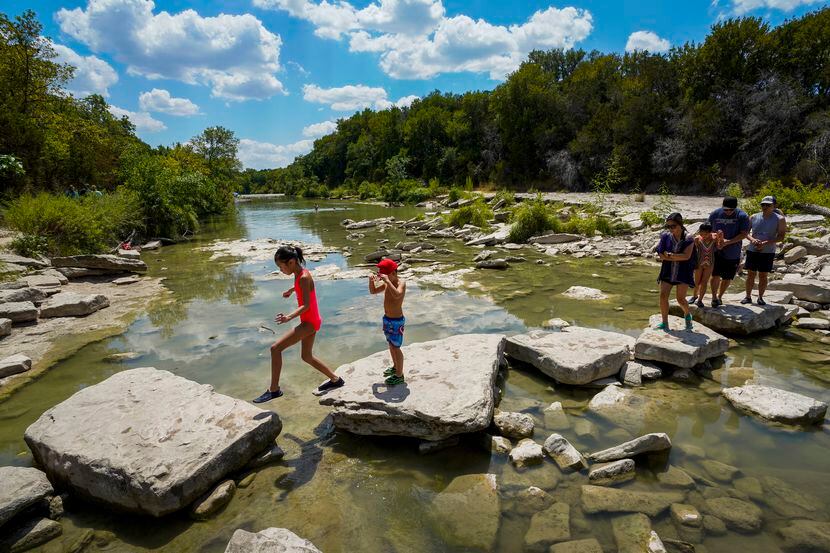 Park visitors cross the Paluxy River at Dinosaur Valley State Park on Sunday, Aug. 23, 2020,...