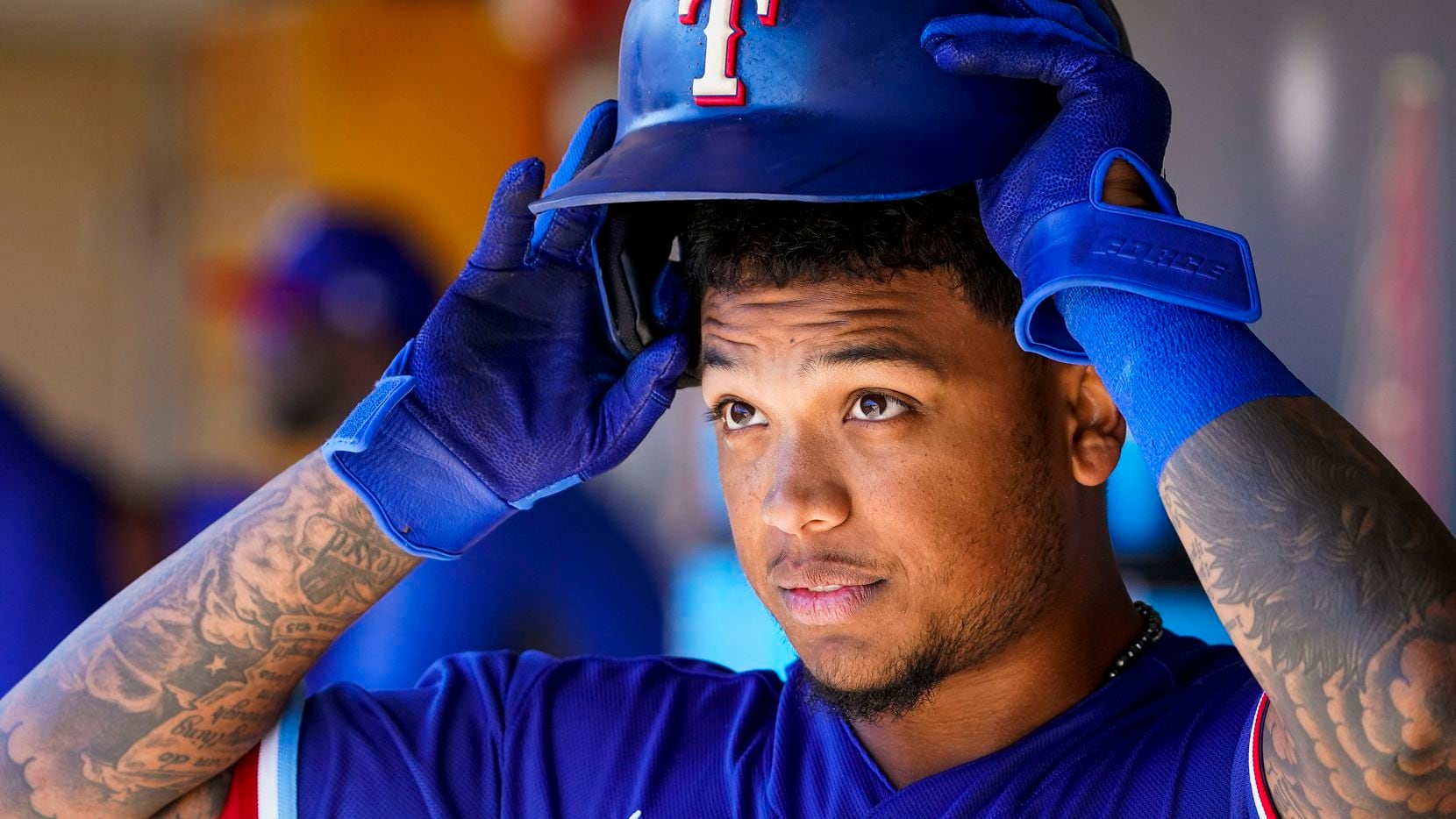 Texas Rangers outfielder Willie Calhoun puts on his batting helmet in the dugout before a...