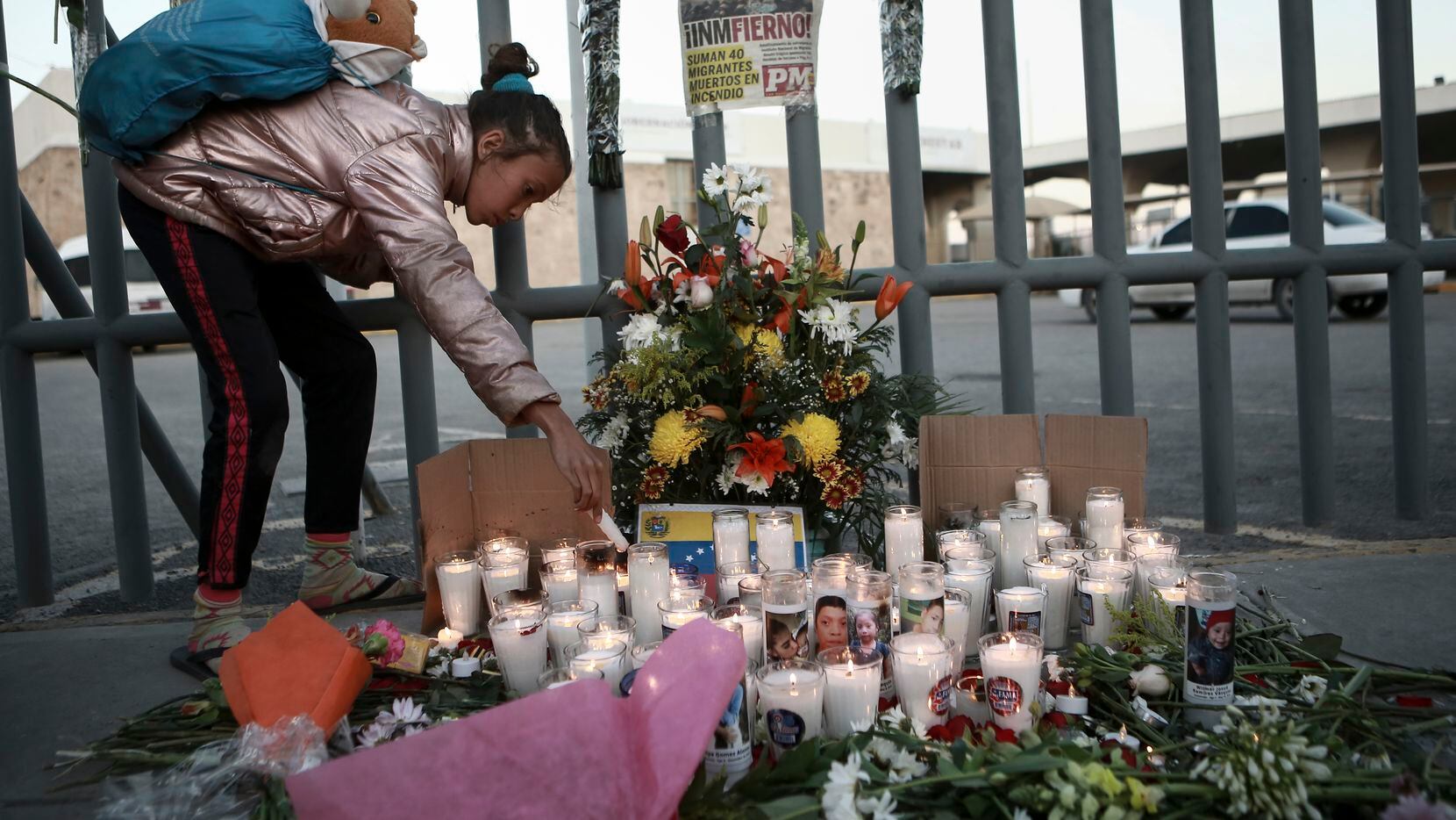 A girl lights candle during a vigil for the victims of a fire at an immigration detention...