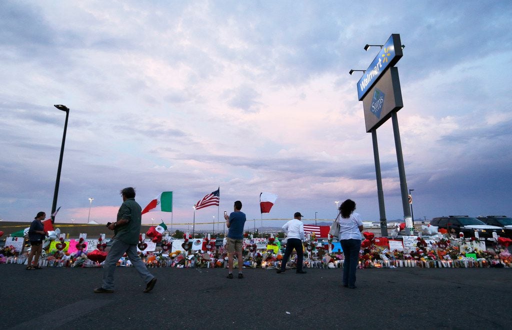 People stood next to 22 crosses Tuesday at a makeshift memorial for victims of Saturday's mass shooting at an El Paso Walmart. On Thursday, a man allegedly armed with a gun and knife was detained in front of a migrant community center, putting the city's residents further on edge.