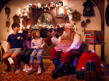 From left: Levi Wozny and his sisters Willa and June Wozny of Dallas listen to Santa as they...