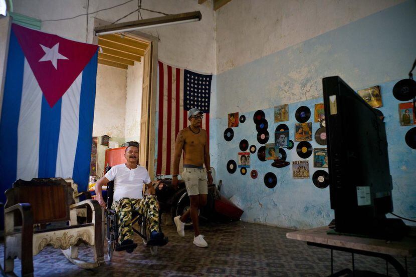 Unas banderas norteamericanas y cubanas cuelgan de la pared de la casa de Armando Ricart,...