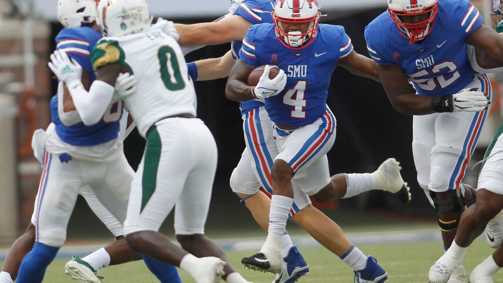 SMU running back Tre Siggers (4), center, bolts into the South Florida secondary for a first...