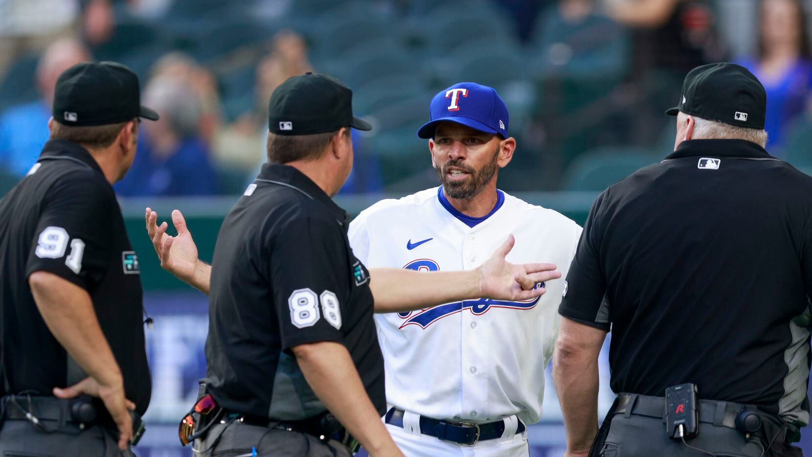 Texas Rangers manager Chris Woodward (8) argues with the umpires after an overturned call...