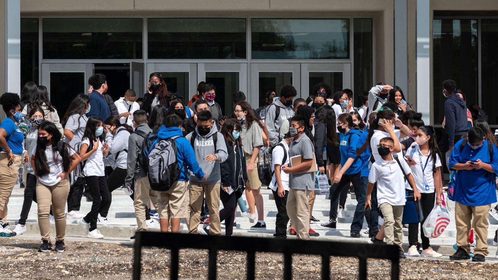 Students gather at the main entrance as they wait for their parents and family to arrive, after the first day of school at E.D. Walker Middle School in Dallas, on Aug. 16, 2021. 
