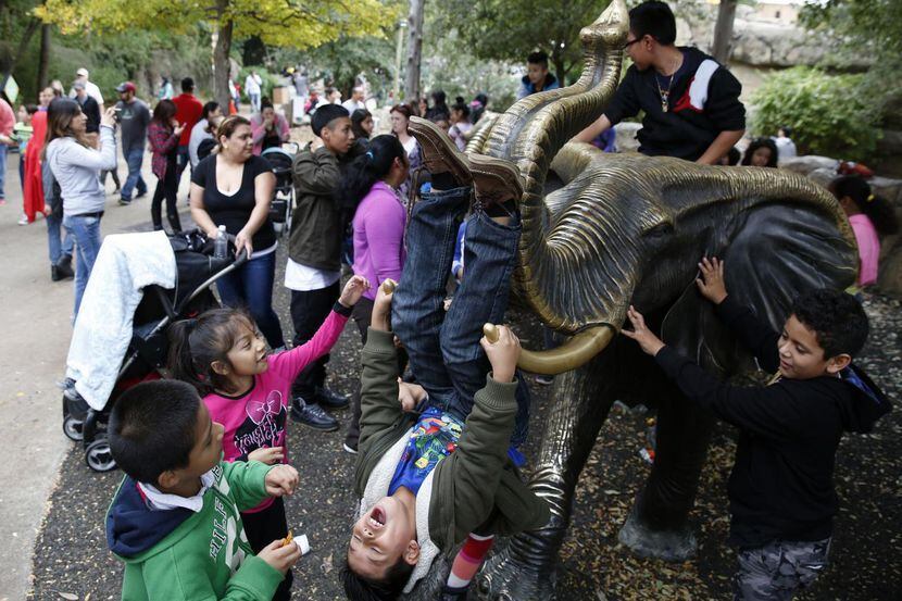 Niños juegan en una figura de metal del elefante, en el zoológico de Dallas, el previo Día...