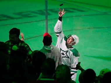 Dallas Stars left wing Jason Robertson tosses a puck to the crowd after being recognized as...