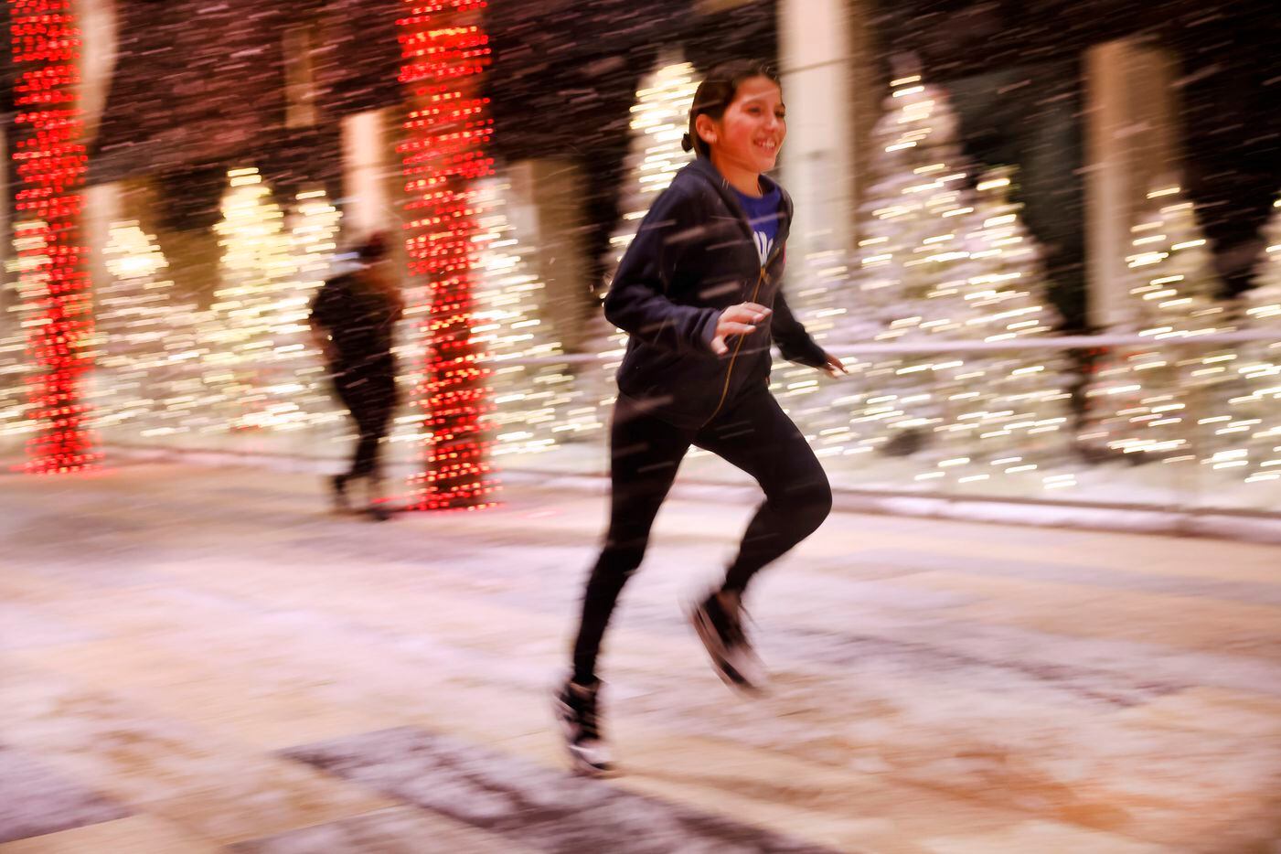 Julia Frankfurt, 11, of Dallas plays in the artificial snow falling along a pathway of palm...