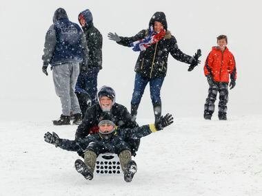 Jacob Hudson, back, and Pearce Smith enjoys their time while sledding during a snowfall as...