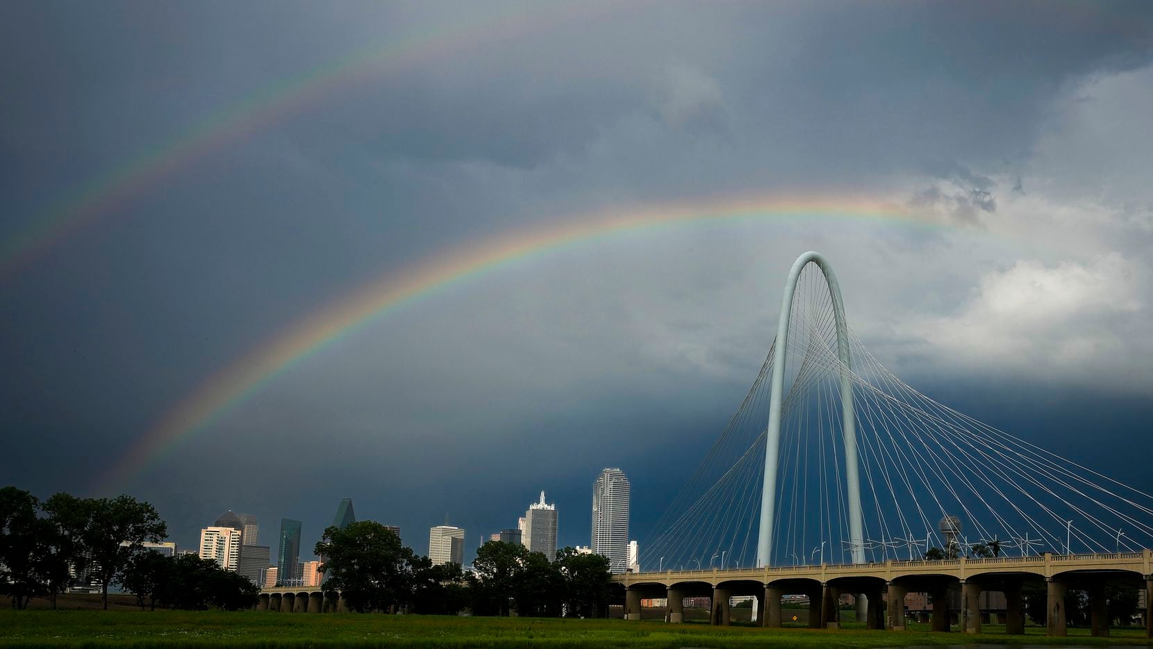 A partial rainbow stretches over the Margaret Hunt Hill Bridge and downtown skyline after a...