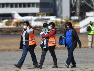 Guatemalan immigration officials use protective equipment as a preventive measure against the new coronavirus, COVID-19, as they receiving Guatemalan migrants deported from the United States, at the Air Force base in Guatemala City, on March 12, 2020.