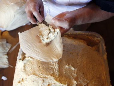 Armandina Flores, 47, places a corn based dough into a corn husk as she prepares tamales to...