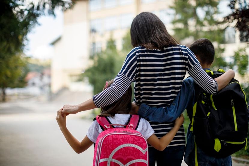 Una madre lleva a sus hijos a la escuela.
