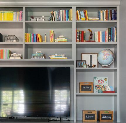 Bookshelves surrounding a TV with boxes and knick knacks arranged among colorful books