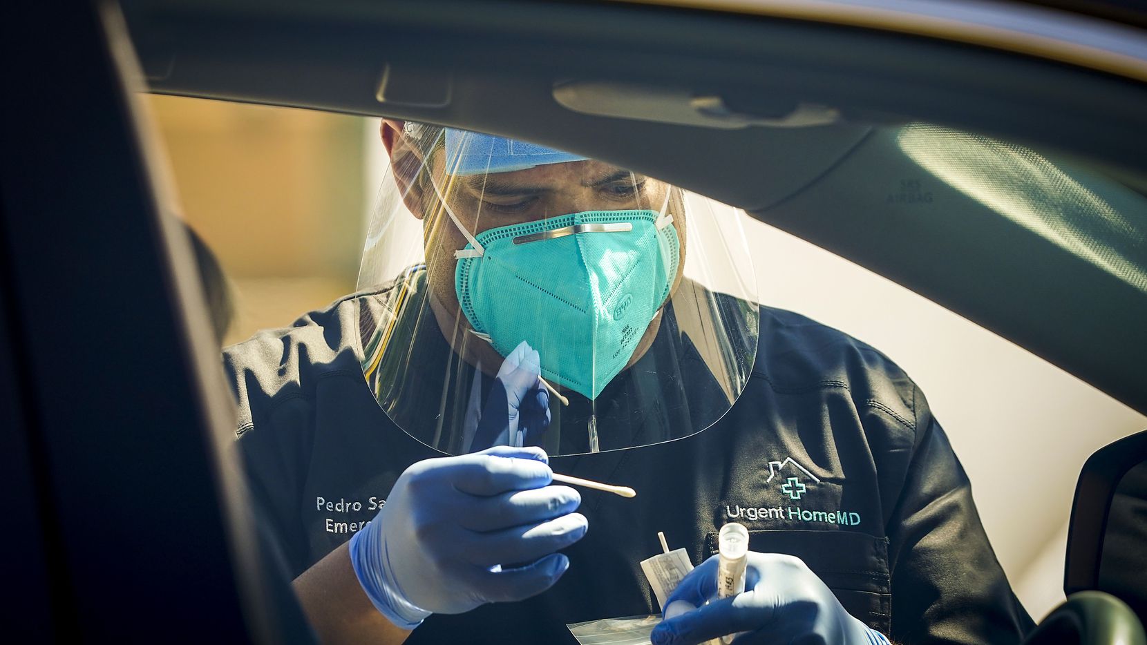 Dr. Pedro Salcido, of Urgent HomeMD, conducts a COVID-19 drive-thru test in a downtown...