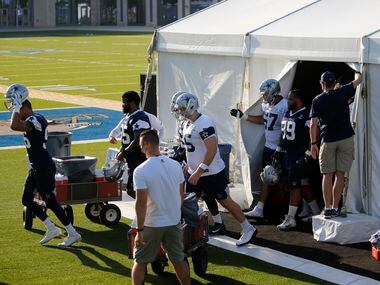 Dallas Cowboys players make their way out of an air conditioned tent for the next stage of...