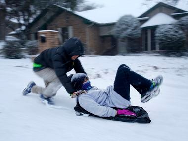 Mitchell Hulme pushes his friend Andew Lim down a steep snow covered street in North...