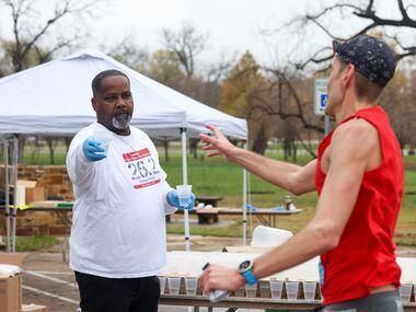 Cliff Piper (left) gives water to runners at the 17-mile mark of the BMW Dallas Marathon on...