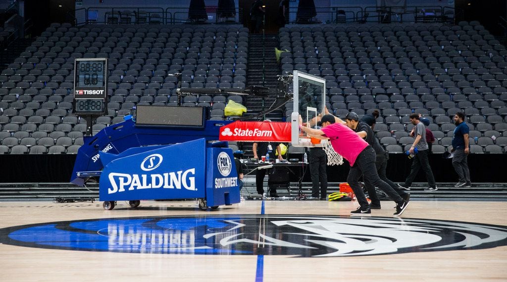 Crews remove a basketball hoop from the court after the Dallas Mavericks beat the Denver...