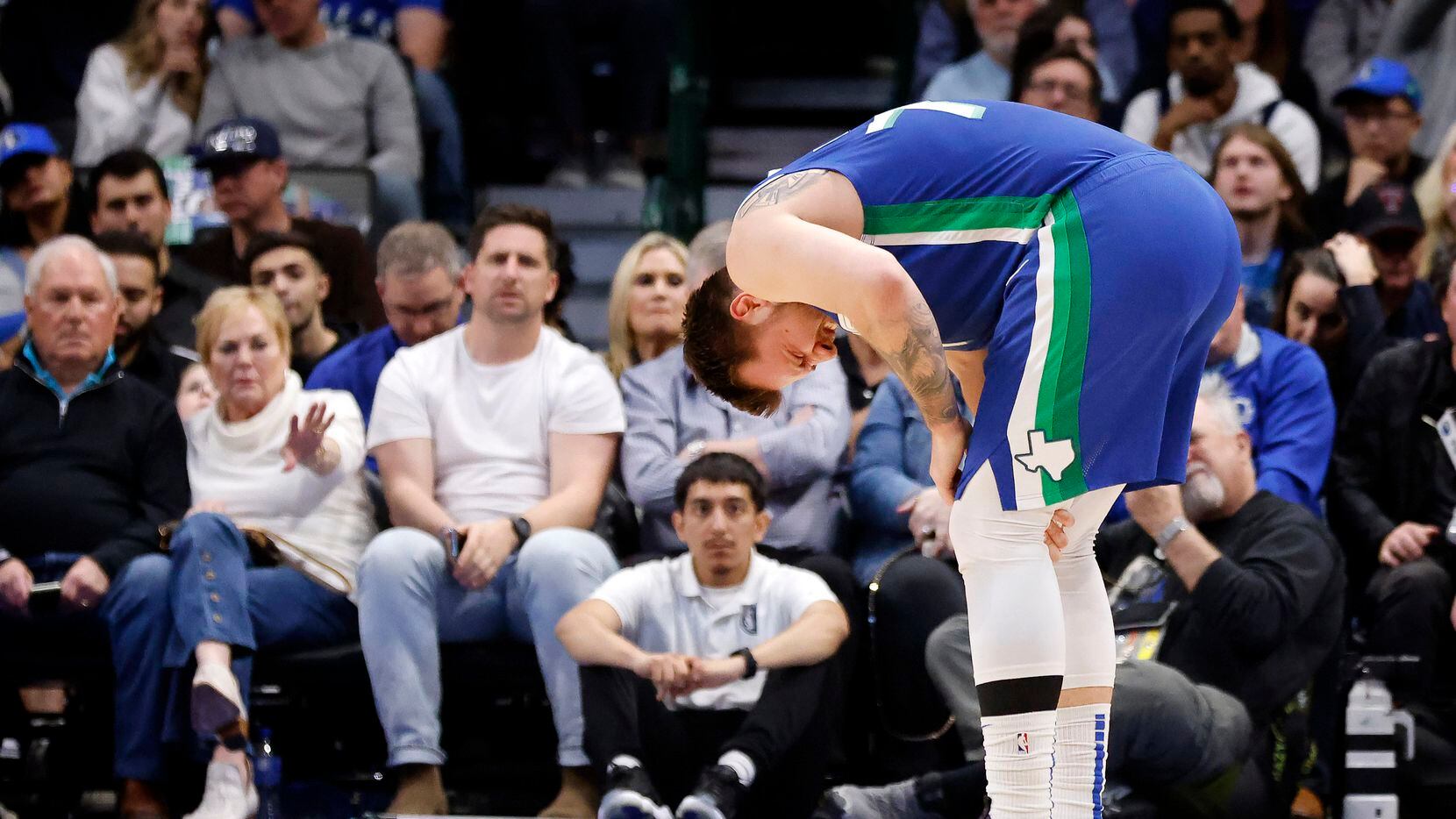 Dallas Mavericks guard Luka Doncic (77) holds his left knee after colliding with Sacramento...