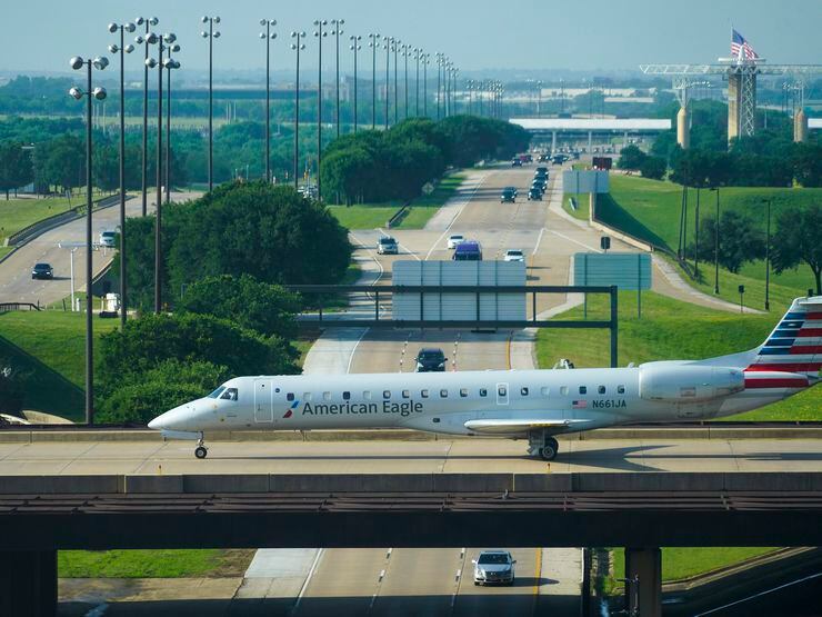 An American Eagle plane taxis on a bridge over International Parkway at DFW Airport on in May.
