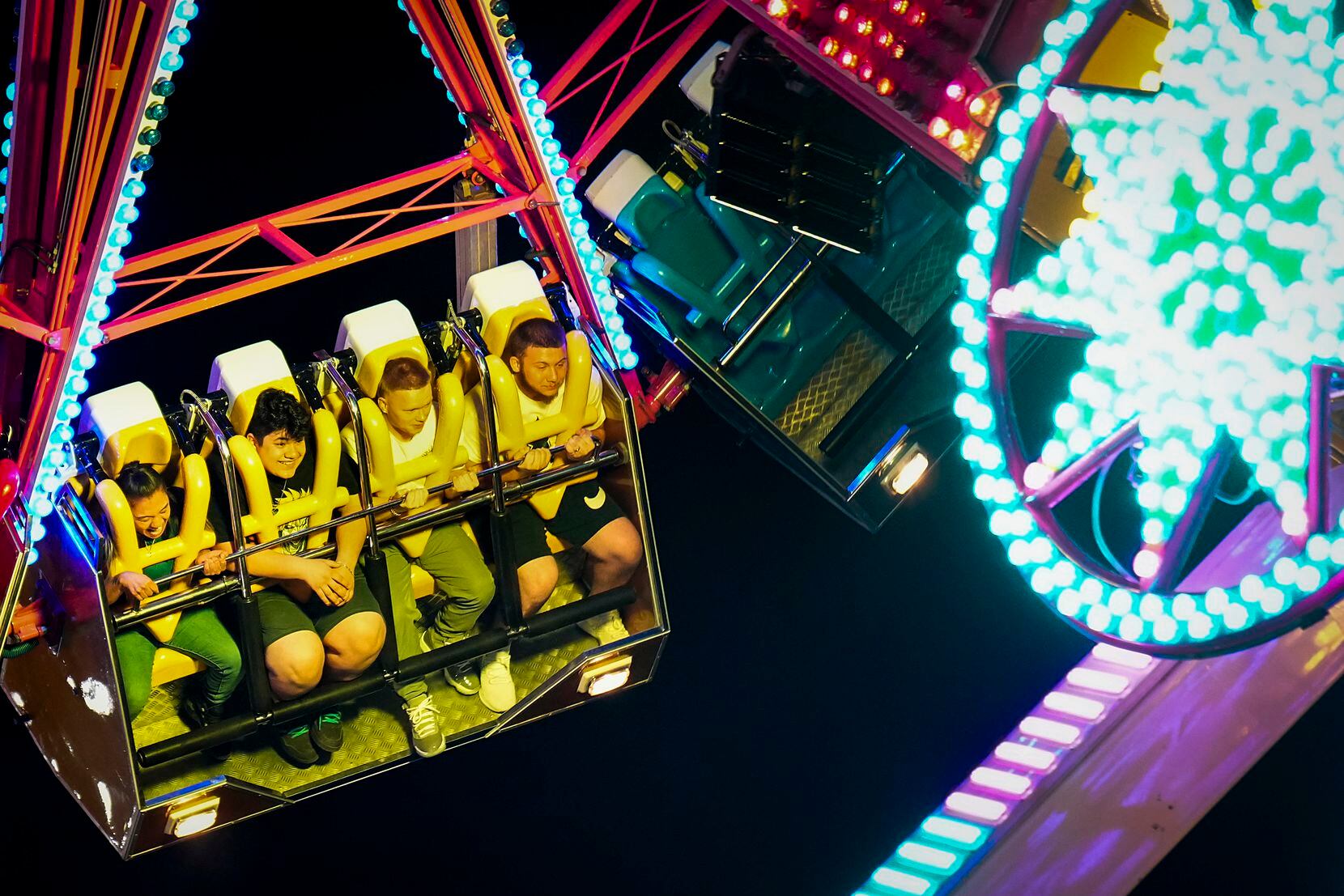 Fairgoers spin on a midway ride on opening night at the State Fair of Texas on Friday, Sept....