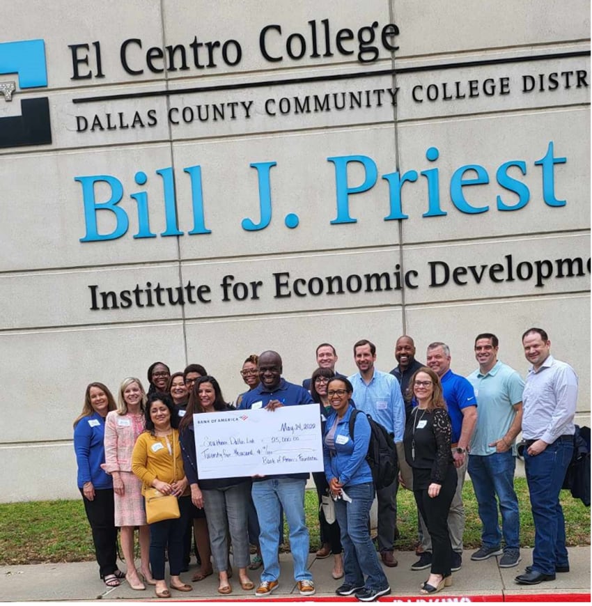 Southern Dallas Link founder and CEO Curtis Corbin holds a check with a group of people in...
