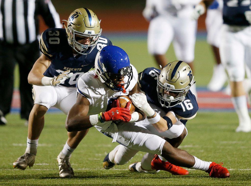 Trinity Christian's Marques Buford (8) is brought down by Austin Regents Charles Benson (30) and Joshua Franklin (16) during the first half of play at the TAPPS Division II State Championship game at Waco Midway's Panther Stadium in Hewitt, Texas on Friday, December 6, 2019. (Vernon Bryant/The Dallas Morning News)