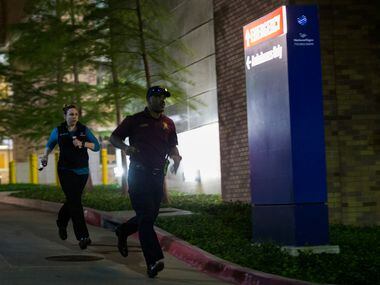 Police officers run away from the emergency room to their cars at Texas Health Presbyterian...
